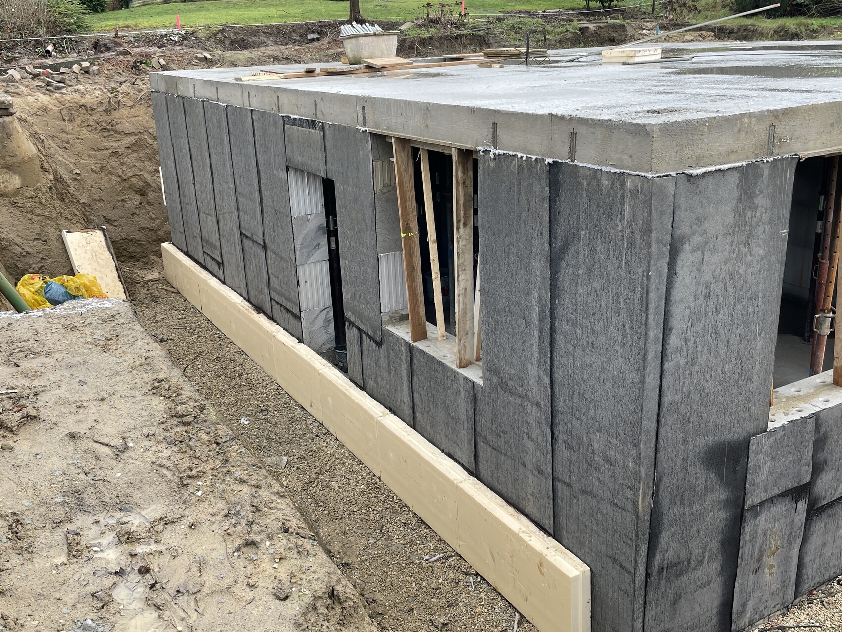 Excavation with gray concrete block walls and window opening in the shell construction.