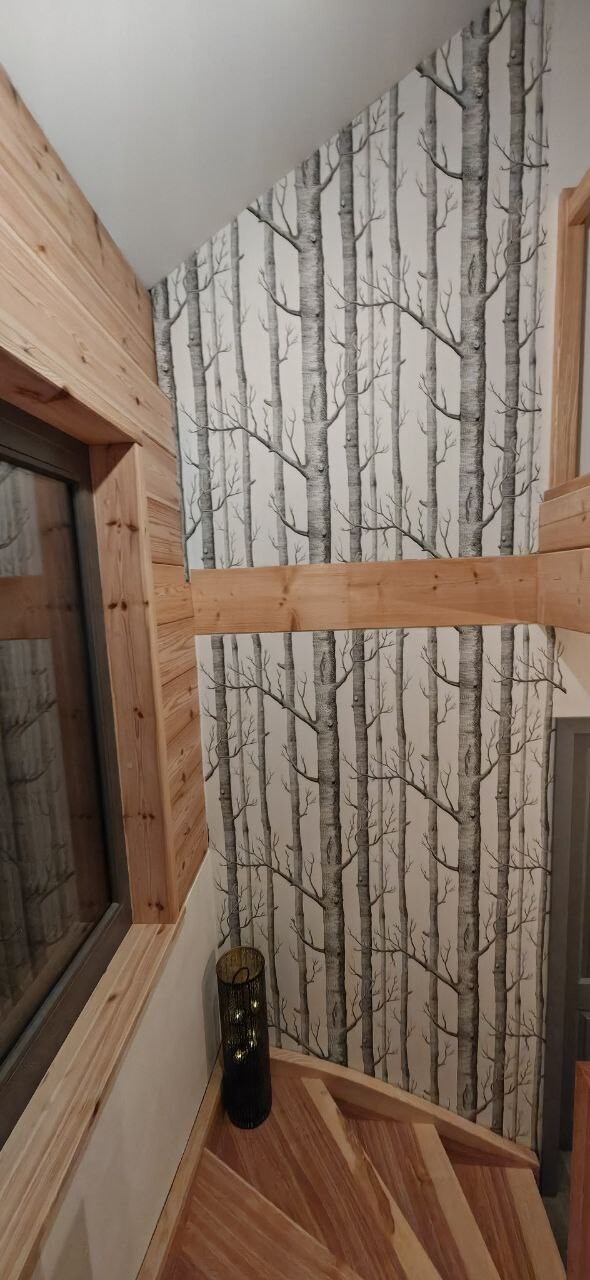 Interior with birch-patterned wallpaper, wood wall paneling, and wooden staircase.