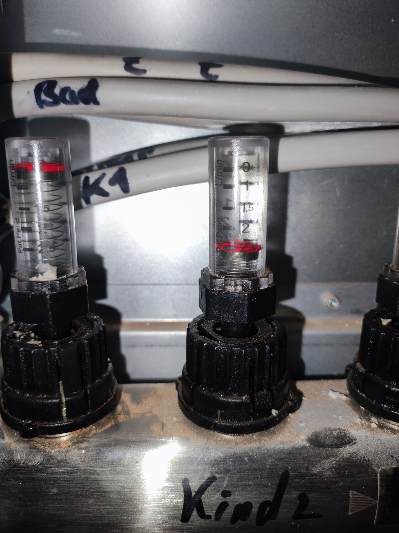 Three transparent measuring tubes with scales and red liquid, mounted on a black base part