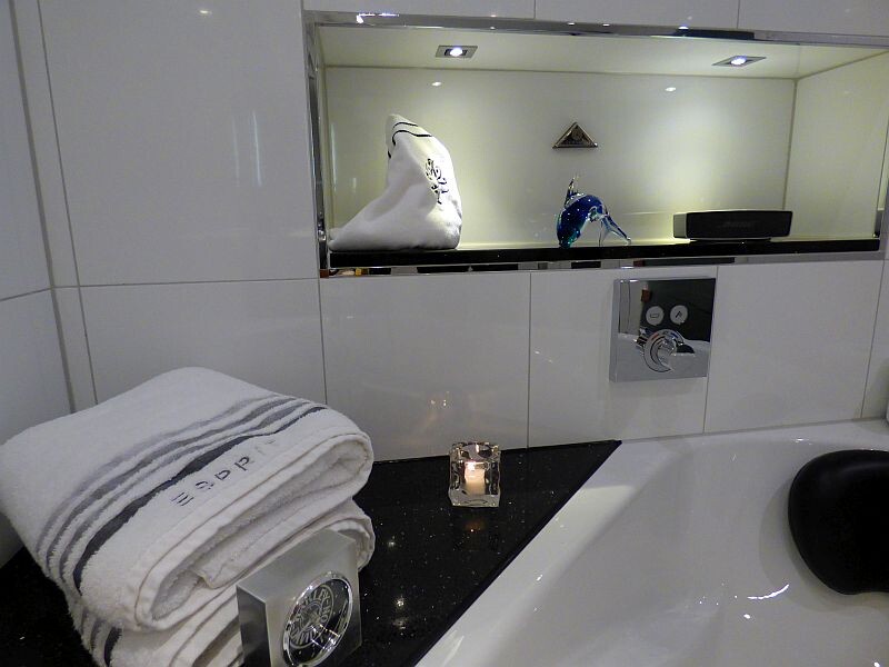 White bathroom shelf with folded towel, candle, and blue seahorse decoration on mirror cabinet