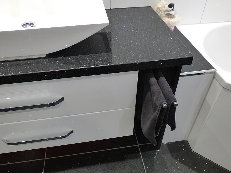 Bathroom: black glitter granite countertop, sink on the left, gray towels on cabinet, plush bear.
