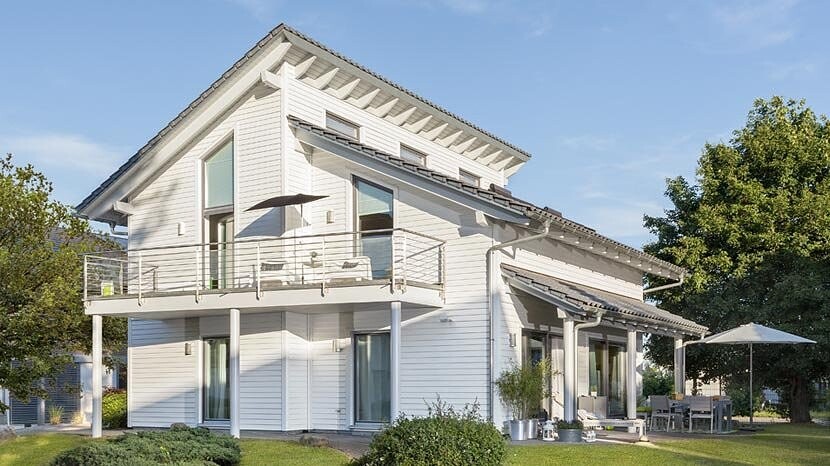 White, modern two-story single-family house with balcony, terrace, and garden.