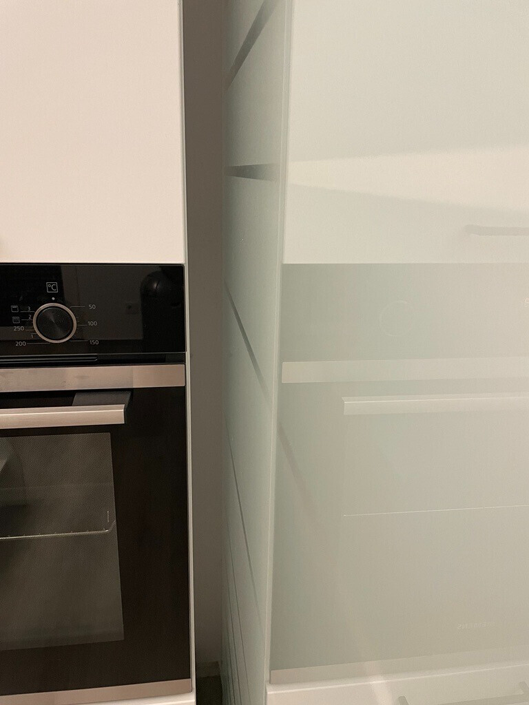 Built-in oven in modern kitchen next to white high-gloss cabinets