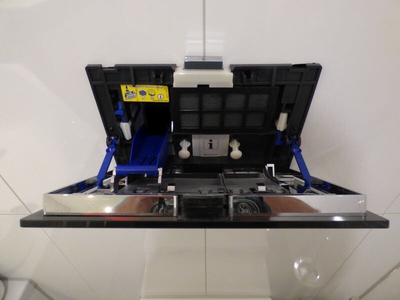 Open lid of a device with blue handles and filter inside.