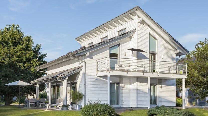 Bright white two-story house with balcony, terrace, and garden.