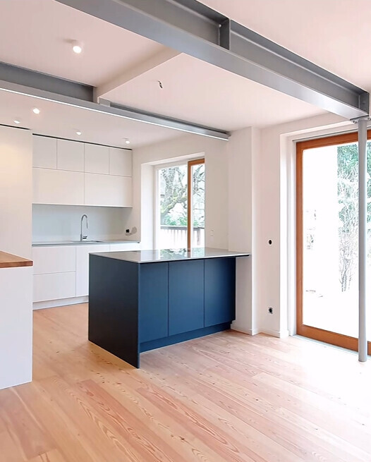 Modern kitchen with island, white cabinets, wood flooring, and glass doors