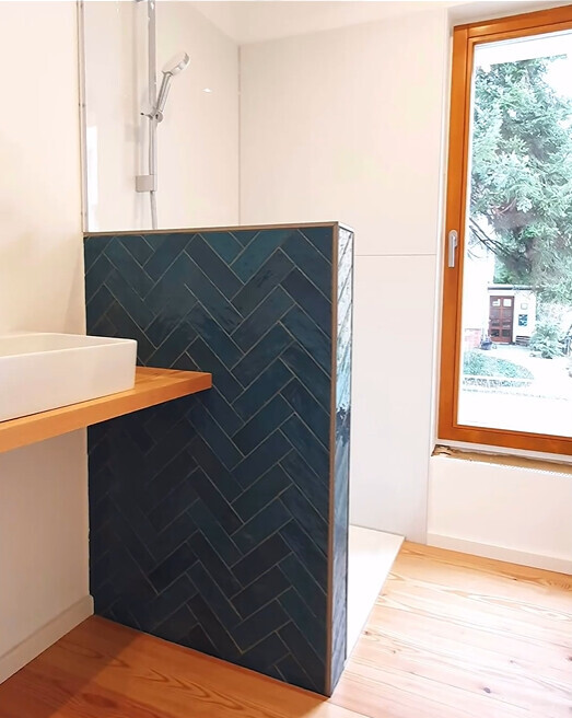 Bathroom: sink on wooden shelf, dark blue tiled partition wall, window to the outside
