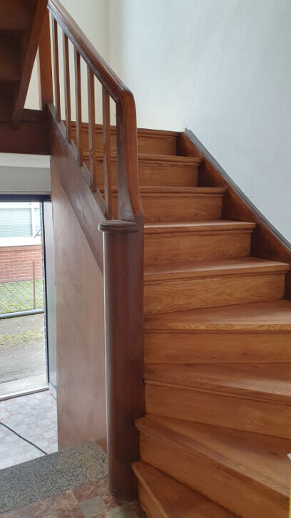 Wooden staircase indoors with railing, wooden steps.