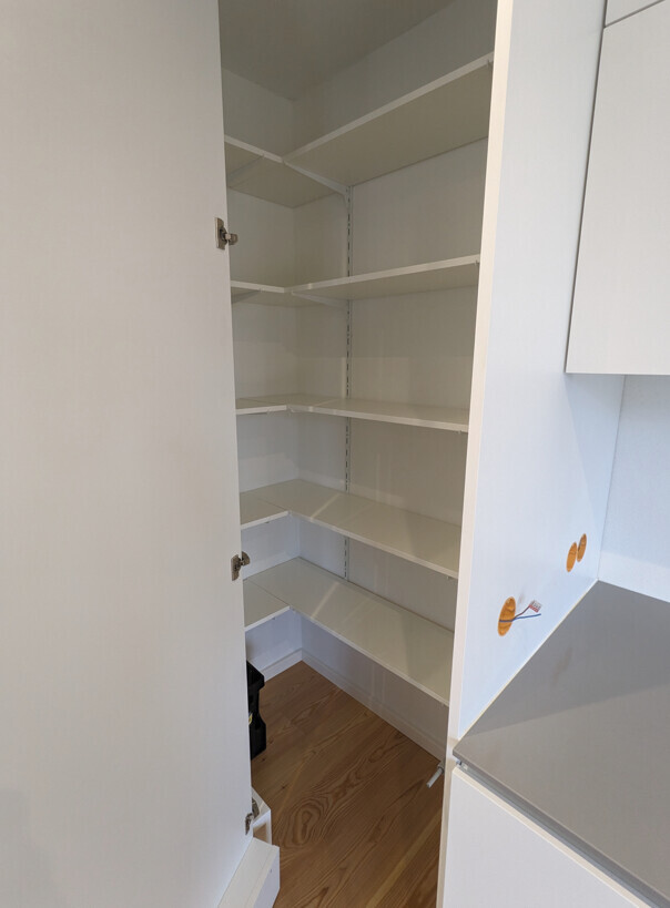 Open white kitchen cabinet with several adjustable shelves, empty.