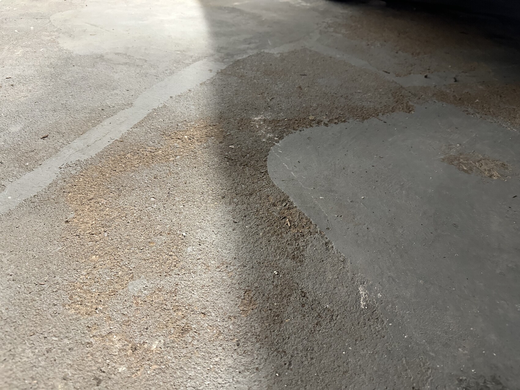 Parking garage floor with dirt and gravel piles; a large round dark spot on the right.