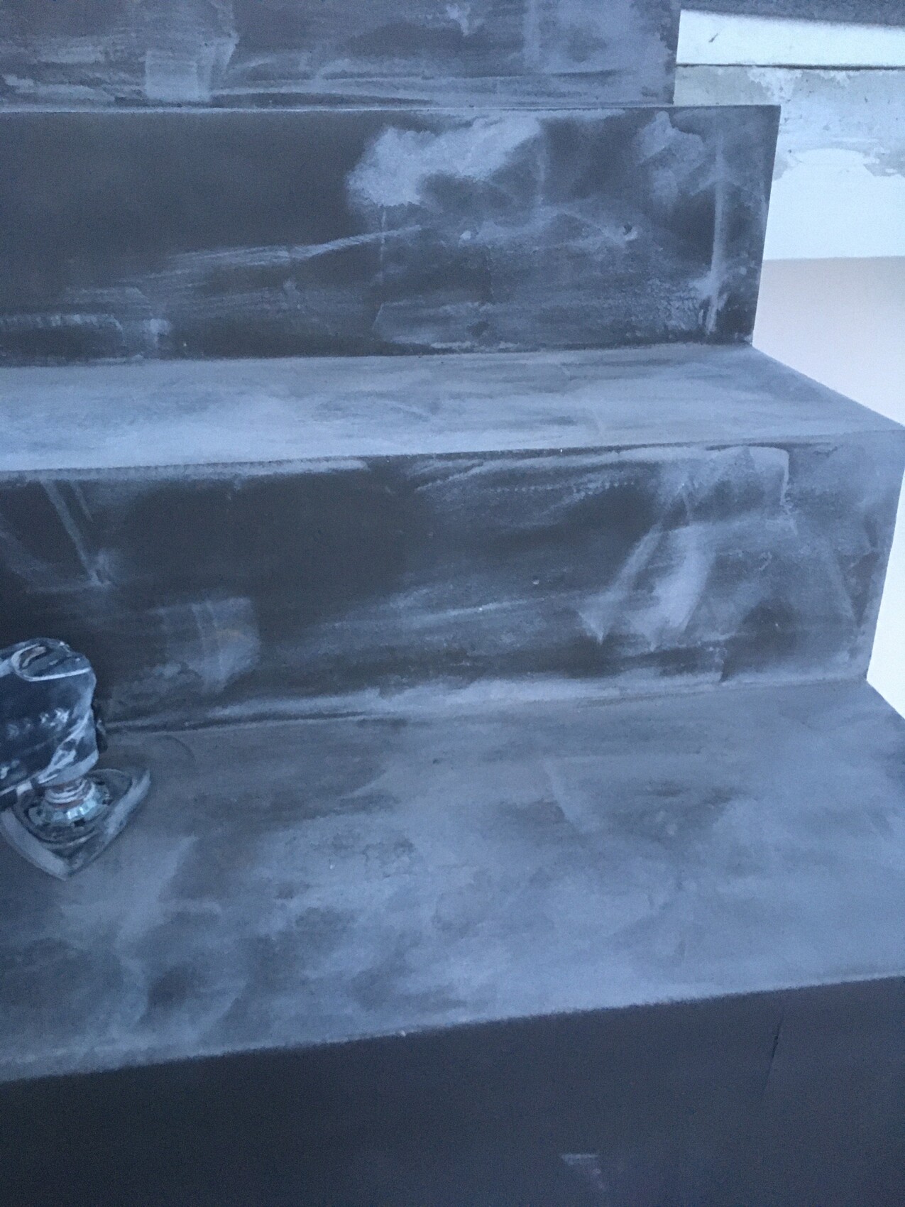 Concrete steps with dust, left sanding machine resting on the bottom step