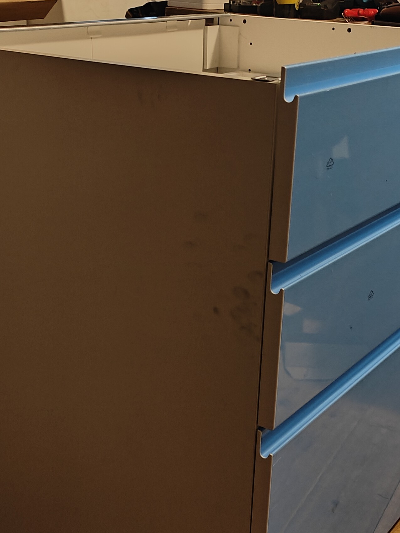 Drawer cabinet with three blue drawers on the right and brown side panel on the left.