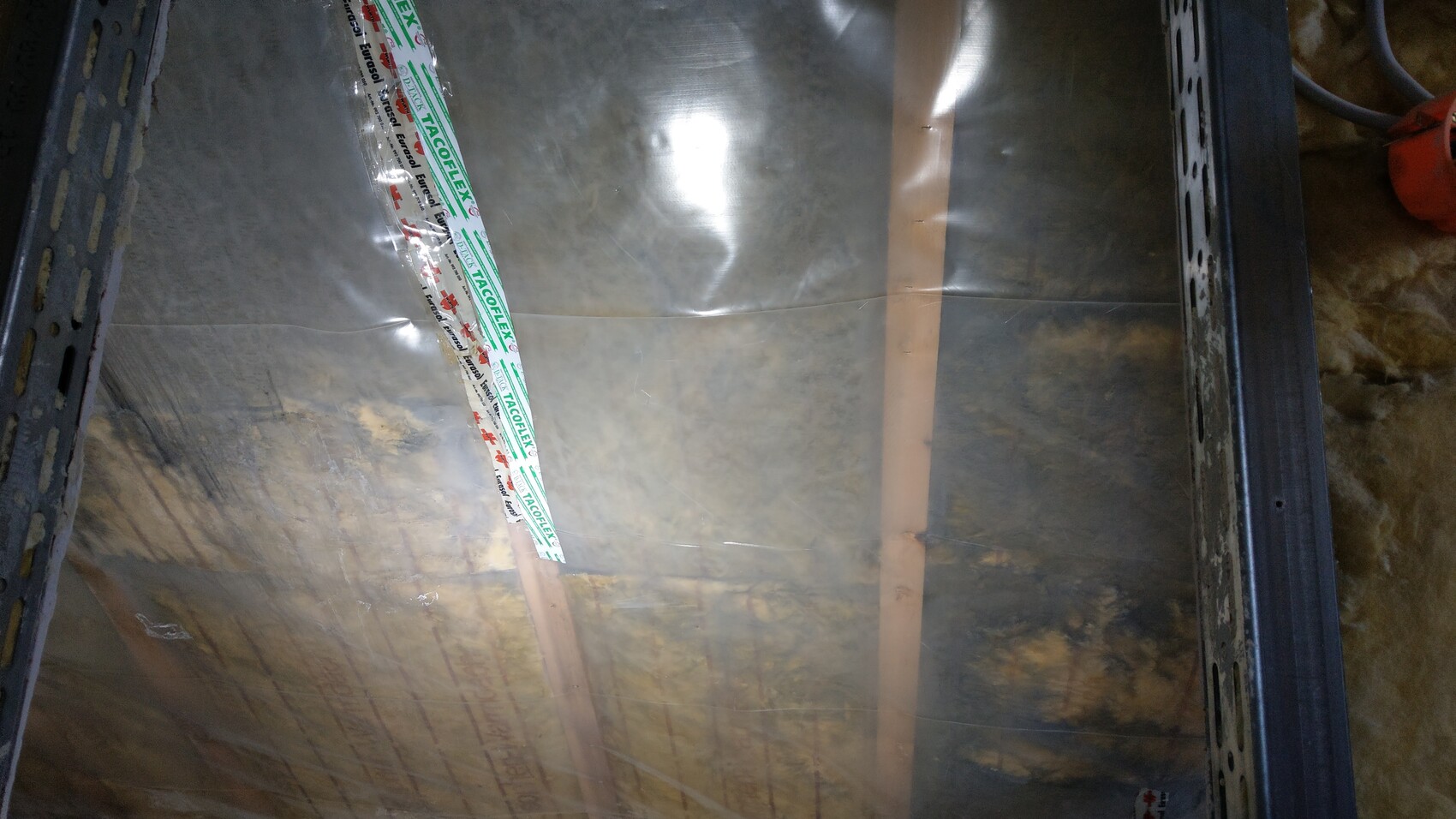 Aluminum foil vapor barrier on construction, TACOFLEX tape applied across it
