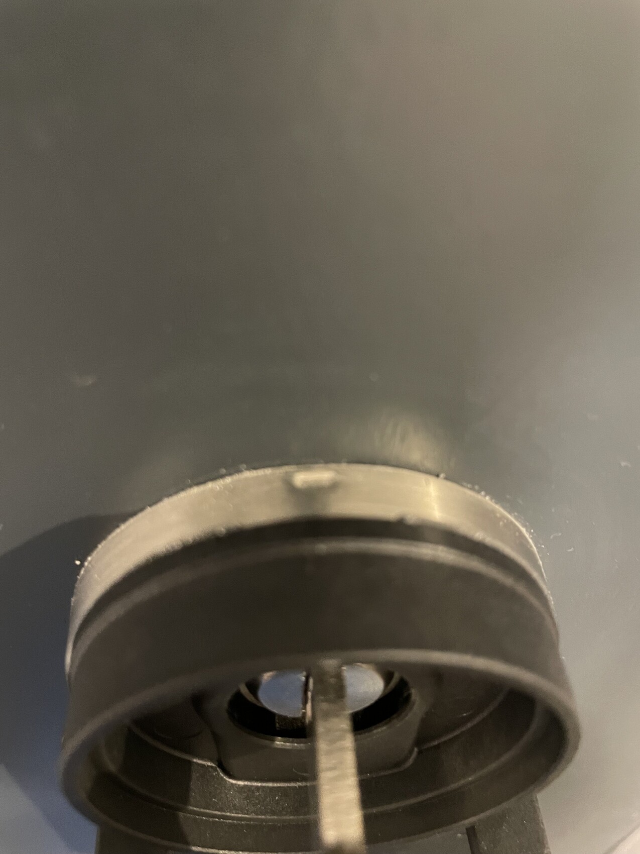 Close-up of a round black mounting part with central opening and rod.