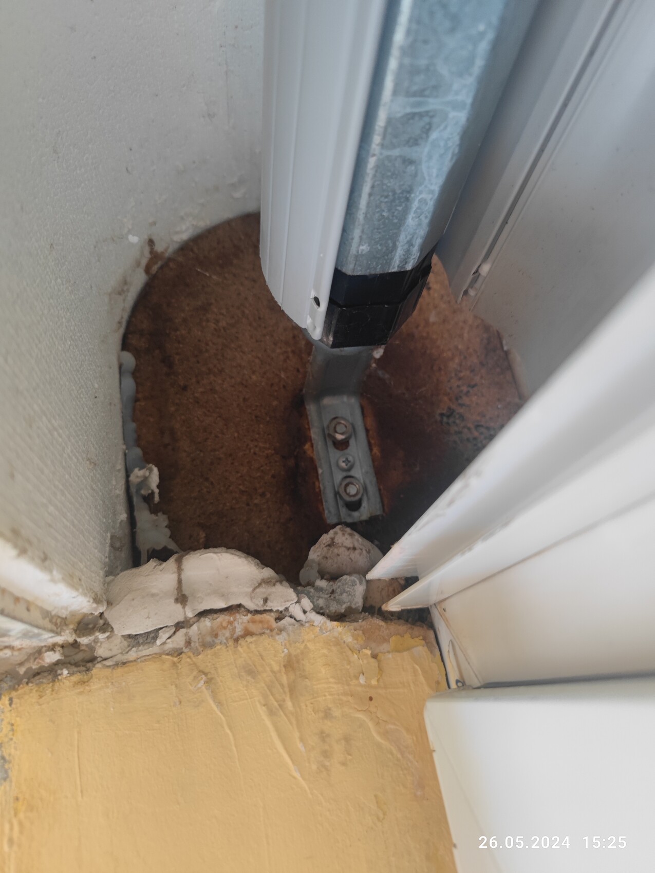 Lower door threshold with rusty metal guide, screws and crumbling plaster.