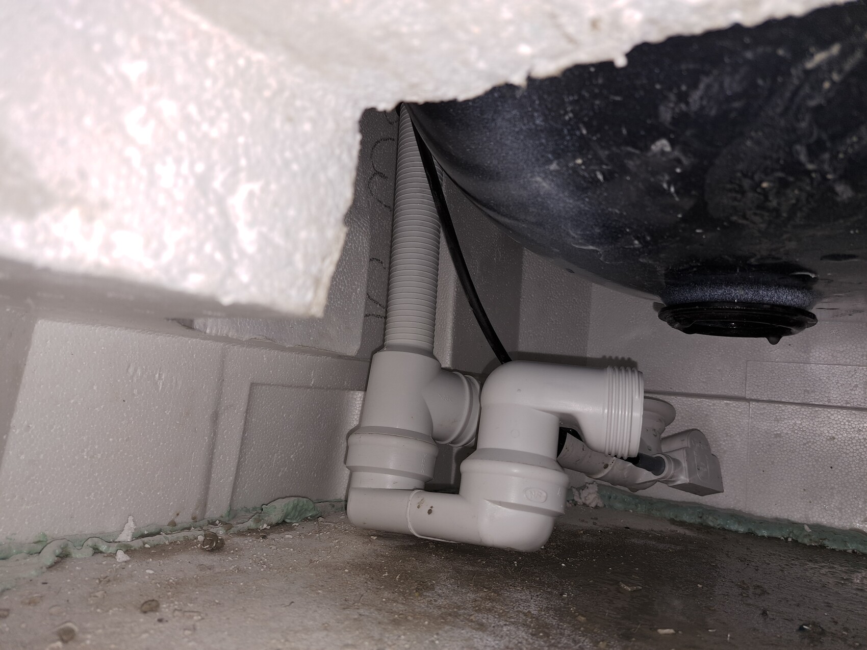 White plastic drain pipes with trap and fitting visible under the kitchen sink.