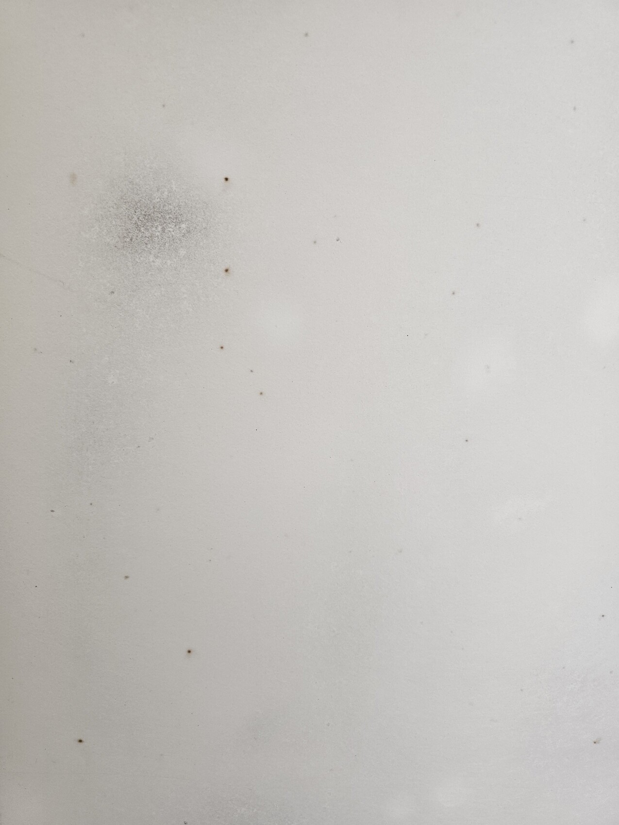 White smooth surface with many small brown stains and a larger stain in the top left.