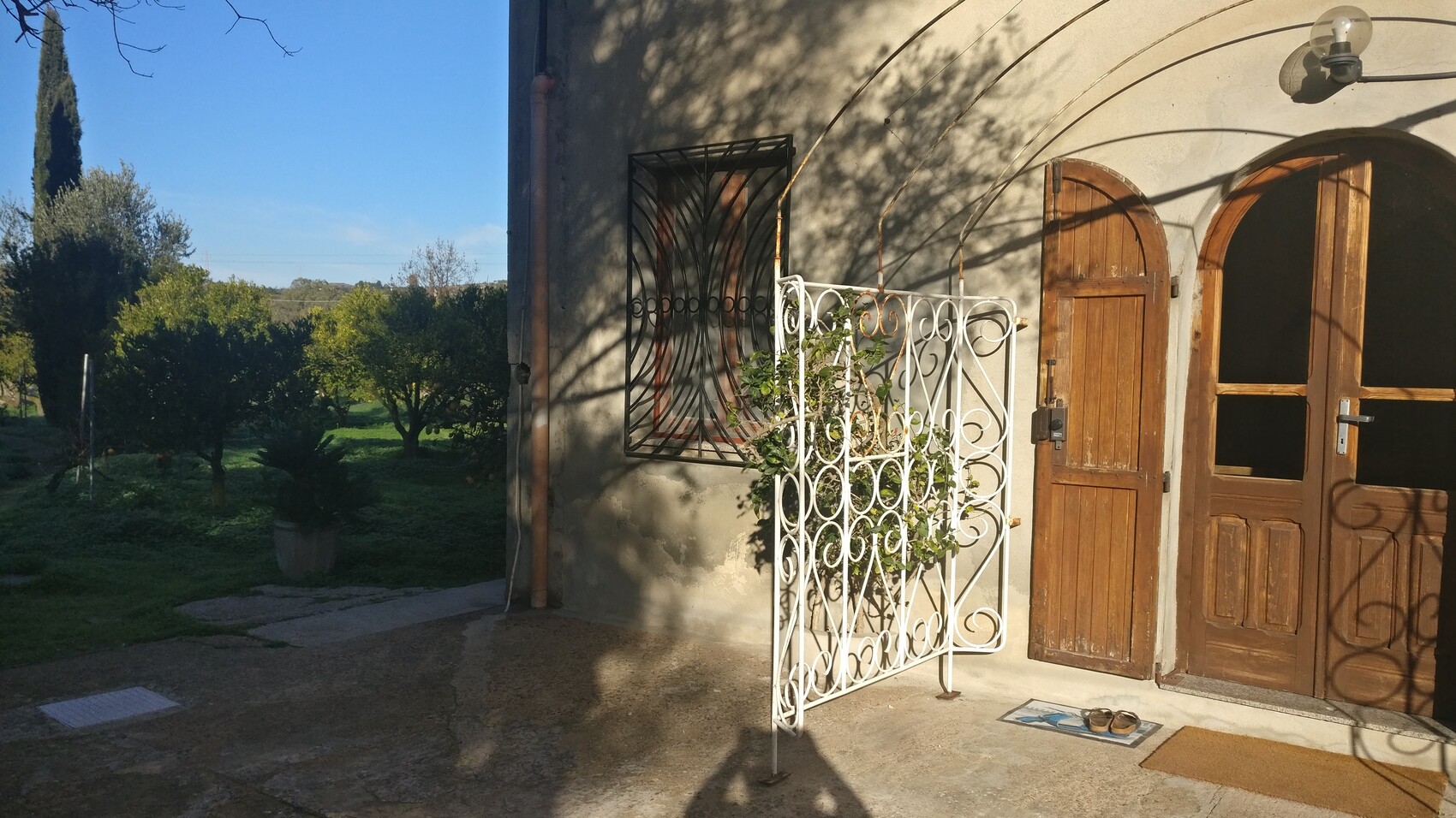 Exterior view of a house with wooden doors, white wrought iron fence, and garden.