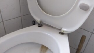 Toilet in the bathroom with open lid and white tiles