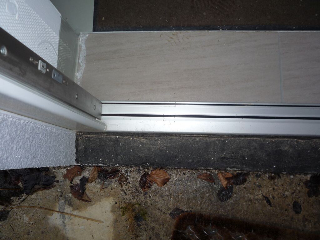 Sliding door track on door frame; outside area with leaves visible.