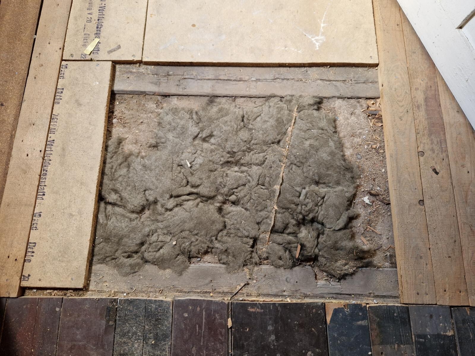 Open floor area on a construction site with insulation material between wooden joists