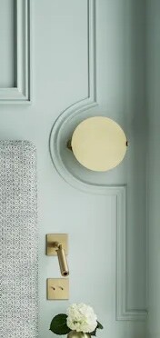 Close-up of a light blue door with a round brass knob and white flower