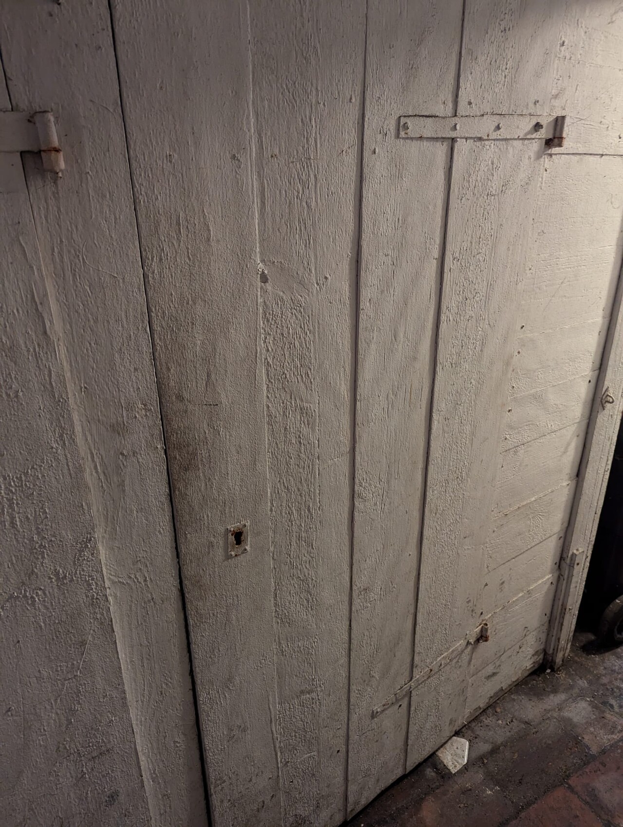 Gray painted wooden door made of vertical boards with rusty fittings, old and worn.