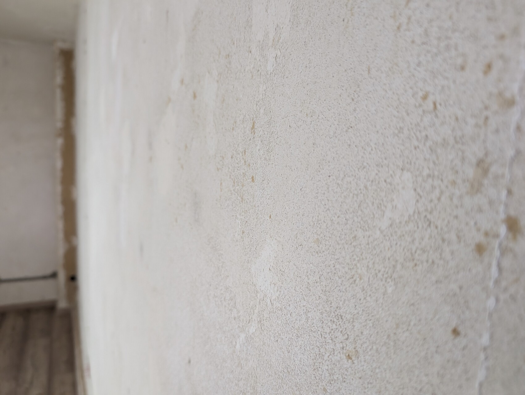 Close-up of a plastered wall with irregular stains; left edge visible.