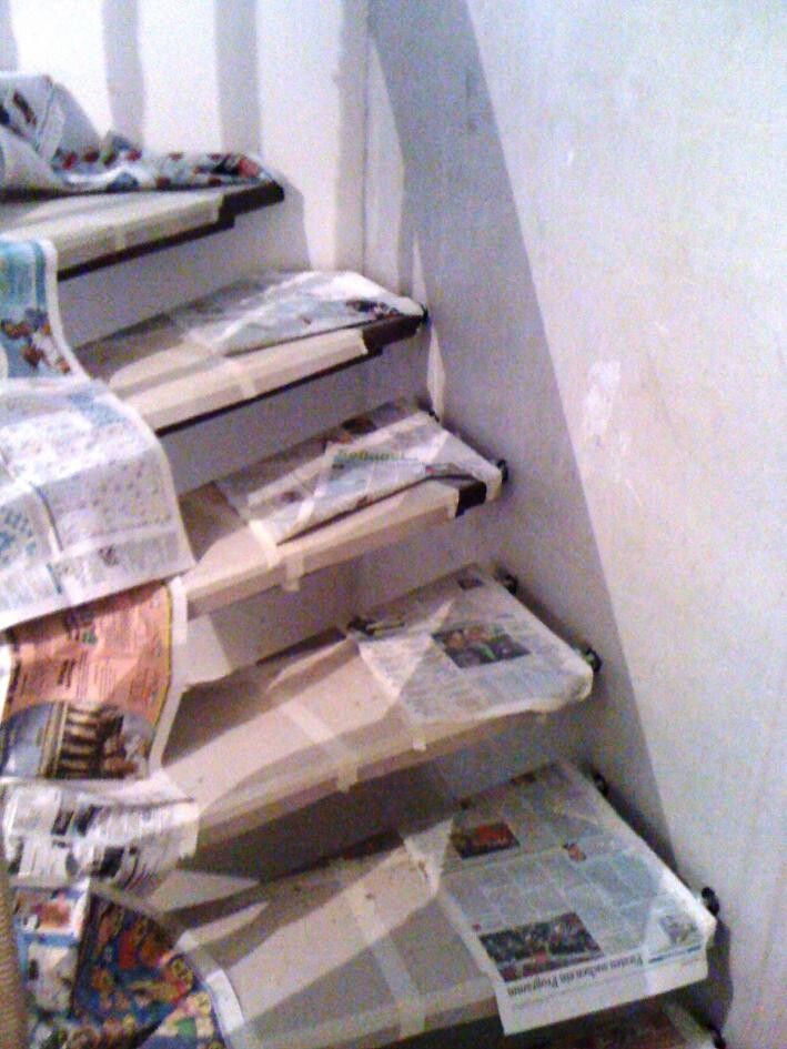 Unfinished staircase during construction, steps covered with newspaper