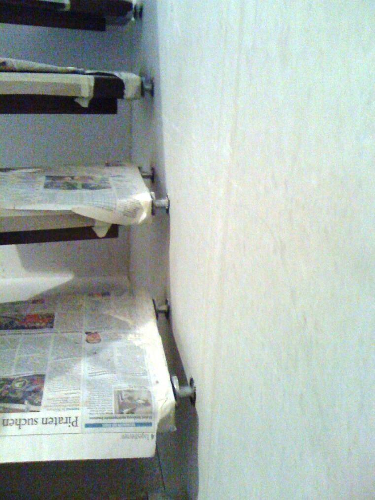 Stack of newspapers wrapped in plastic on metal shelves in a storage room.
