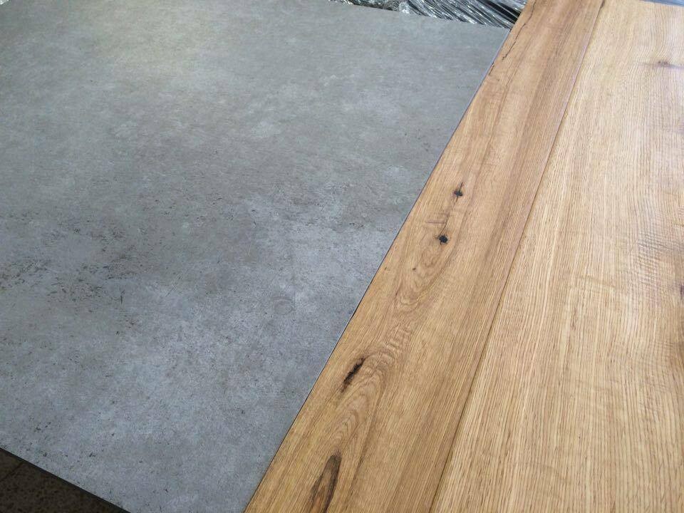Wood plank table edge next to gray concrete floor, visible nails.