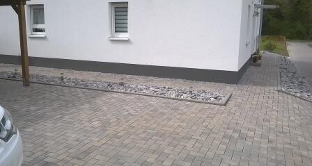 White house facade with two windows and paved forecourt with stone surface