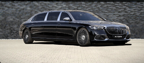 Black luxury sedan parked in front of a gray stone wall on a paved courtyard