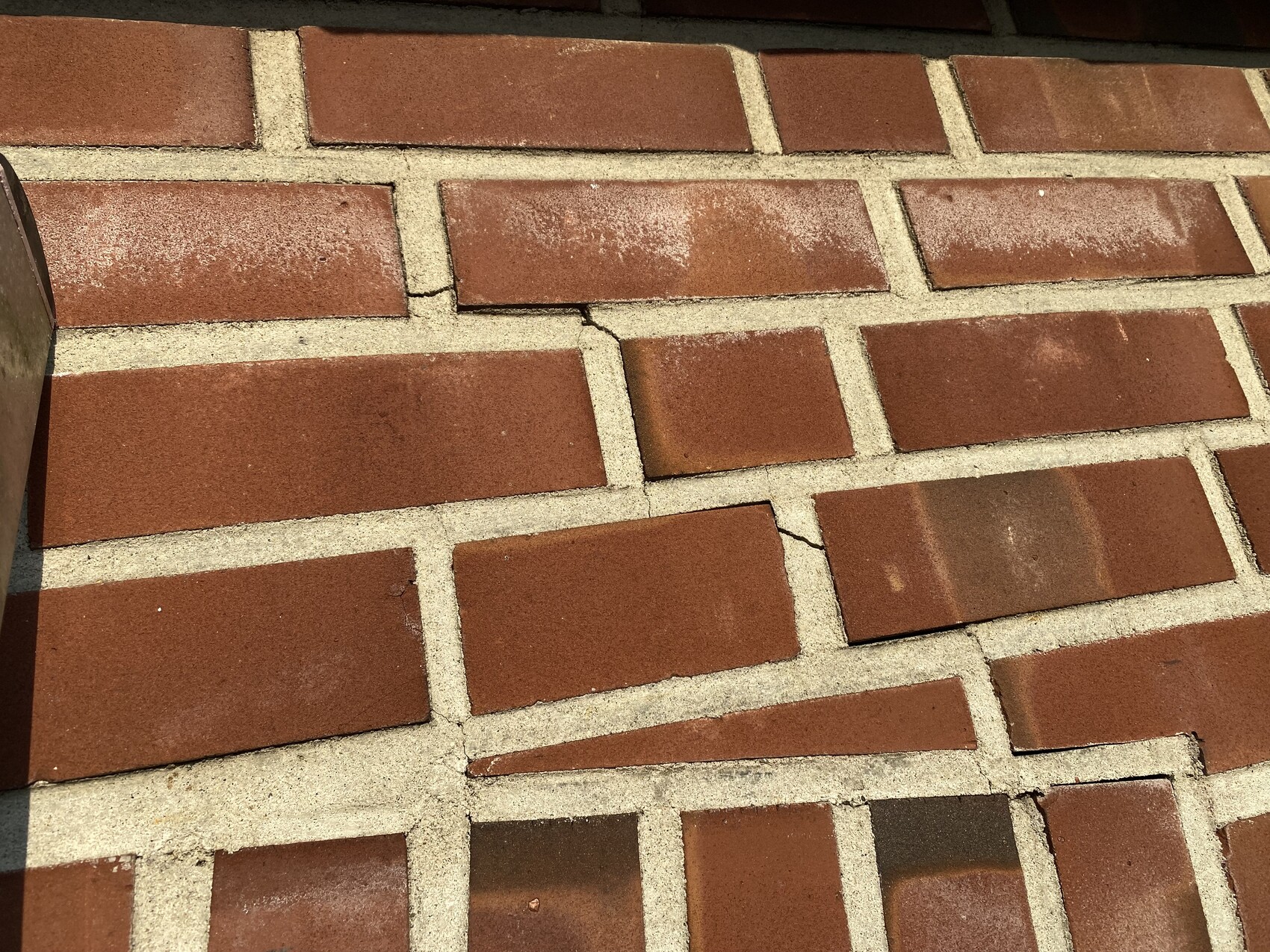 Close-up of red bricks with light gray joints; visible cracks and dust stains.