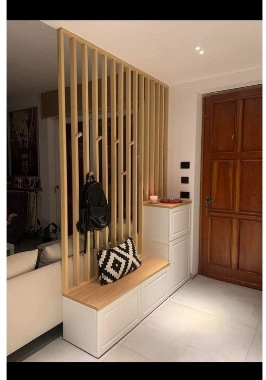 Hallway with wooden lattice partition, bench with storage, cushions; backpack hanging on the slats.