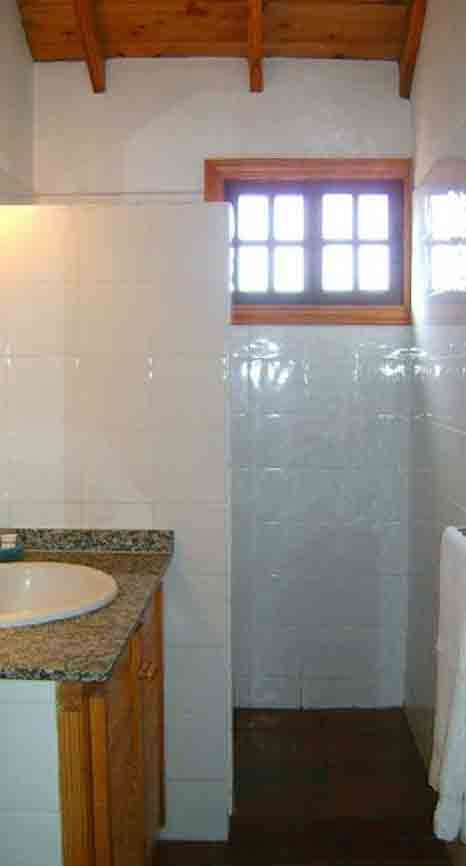 Small bathroom with wooden and granite washbasin, white tiles, wooden window frame