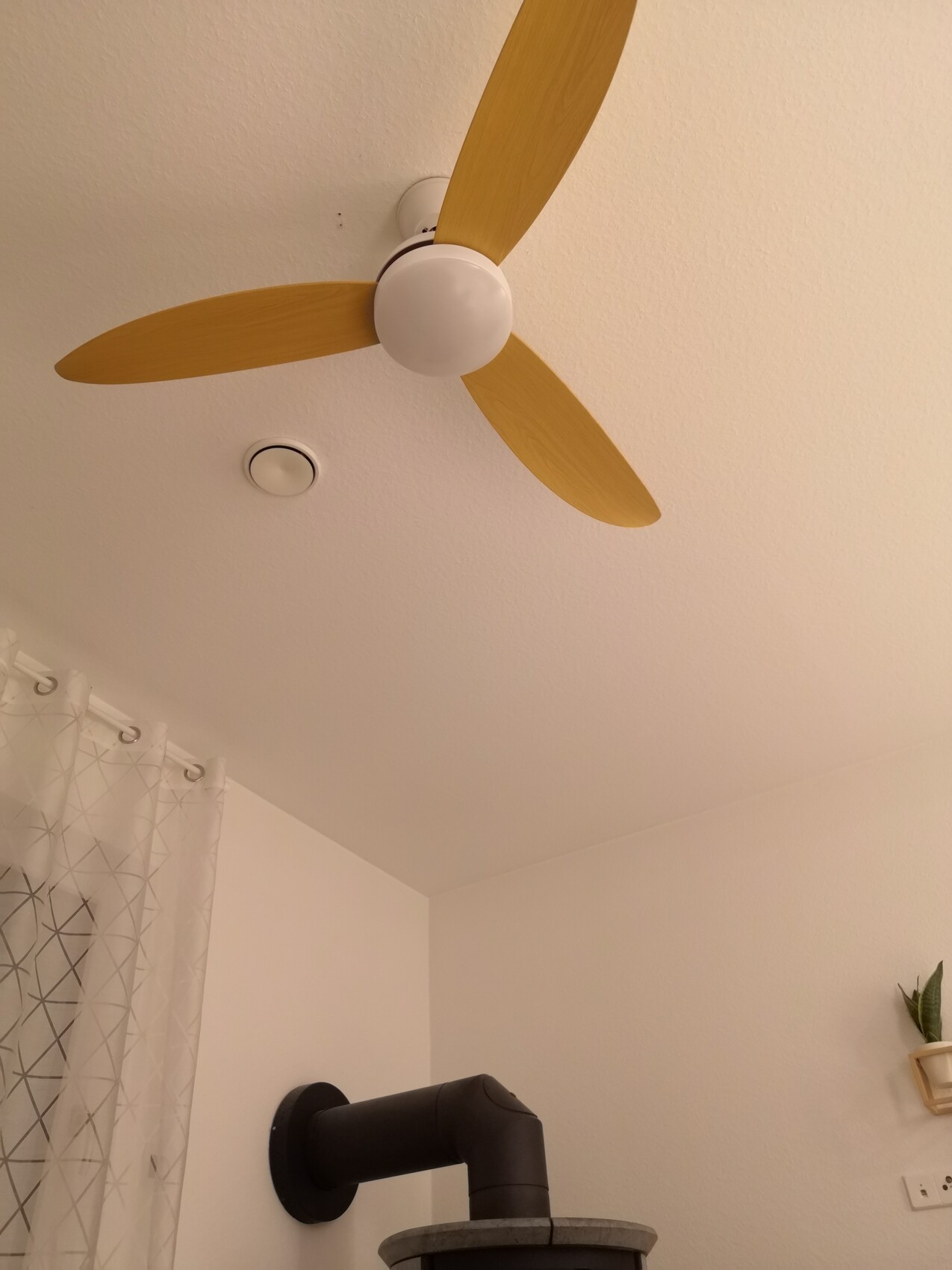Ceiling fan with three wooden blades on white ceiling; bathroom with visible shower.