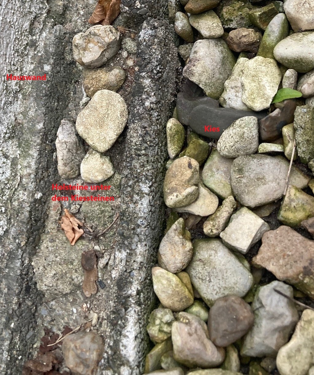 Close-up of a rough stone wall with gravel beside it