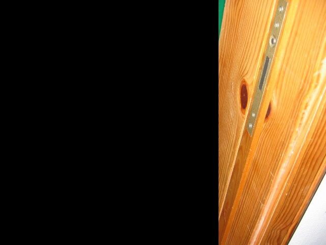 Close-up of a wooden door frame with metal fitting and screws