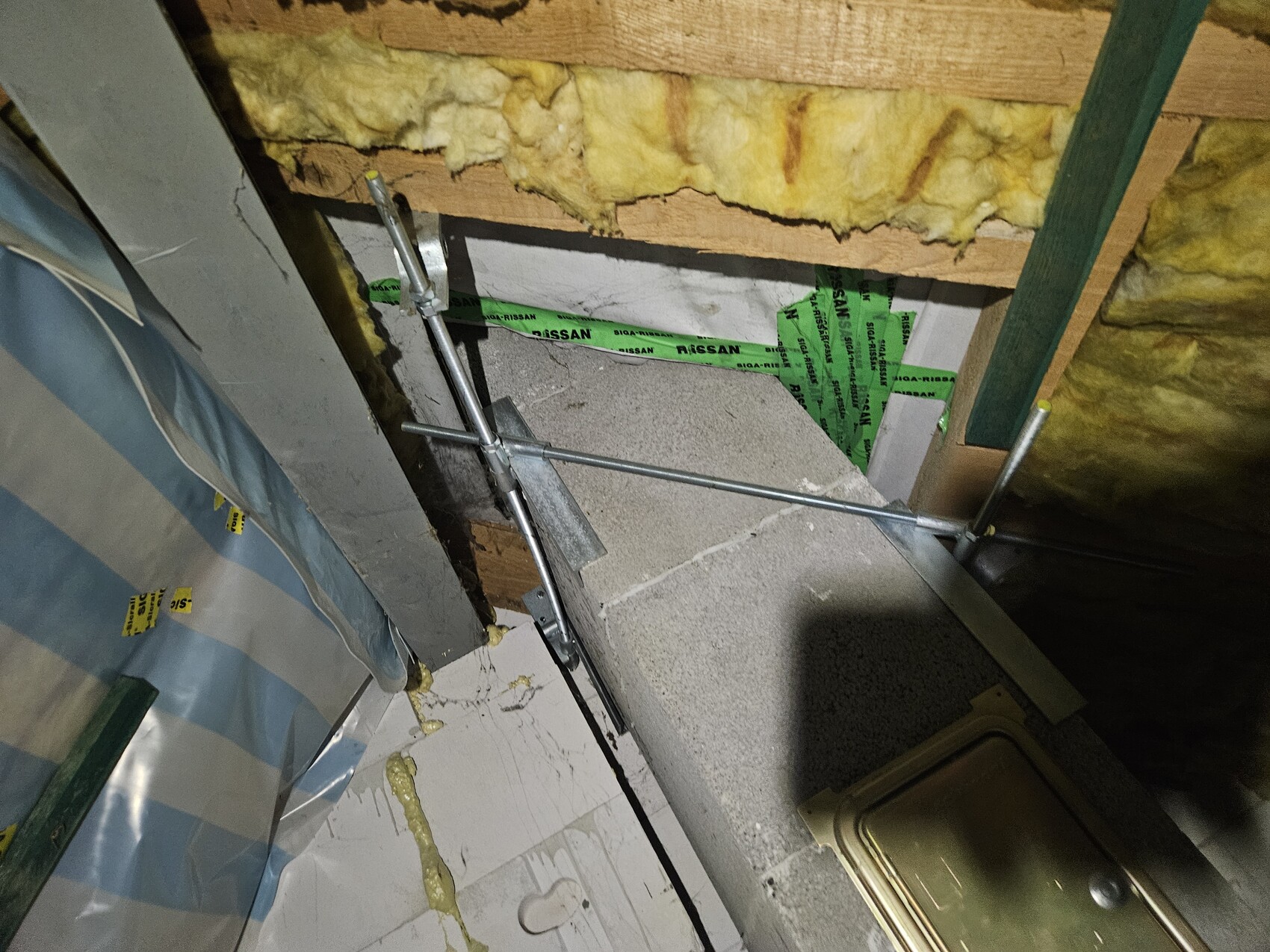 Baustelle im Haus: gelbe DĂ€mmwolle zwischen Holzrahmen grĂŒne Abklebeband, Metallstangen, Betonplatte.