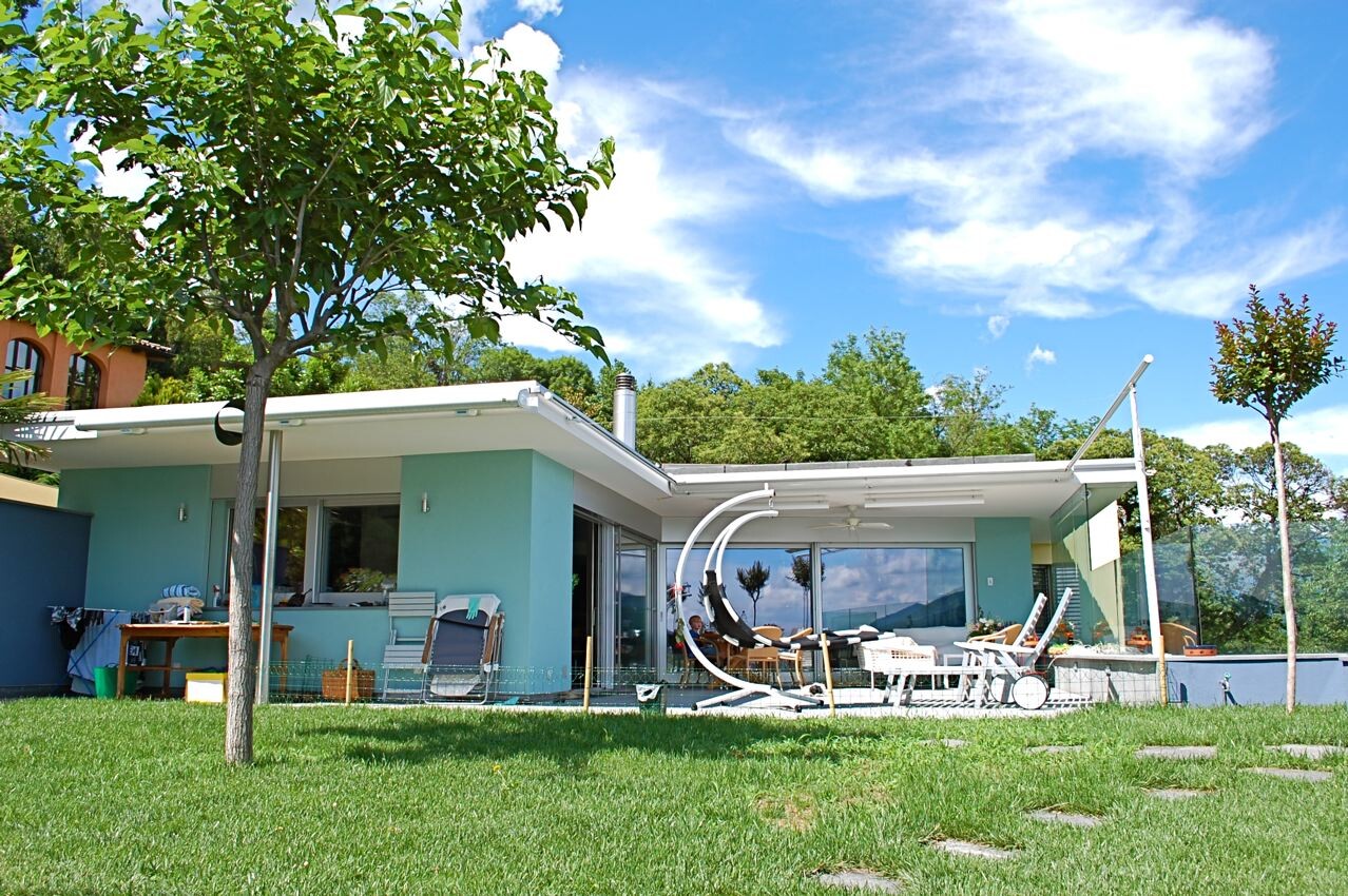 Modern detached house with terrace, lounge furniture and green garden