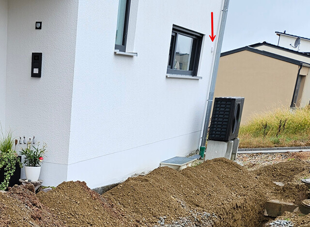 White house facade, excavation at foundation, window and outdoor HVAC unit visible