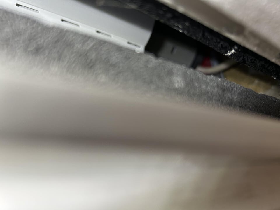 Close-up of a metal housing with three ventilation slots and visible cables.