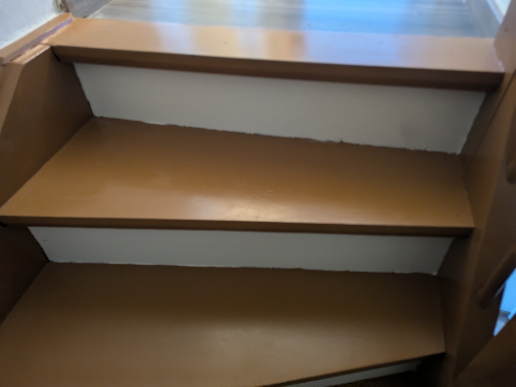 Three-step brown wooden staircase with stringers, indoor area