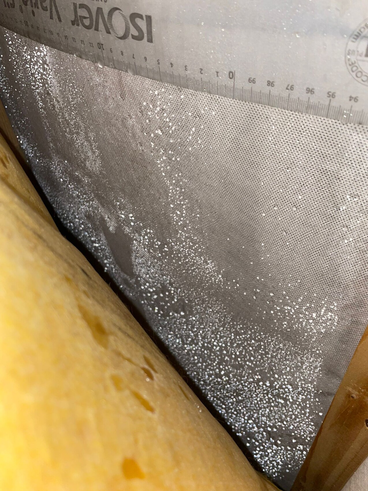 Yellow insulation wool in front of silver ISOVER insulating foil with white particles.