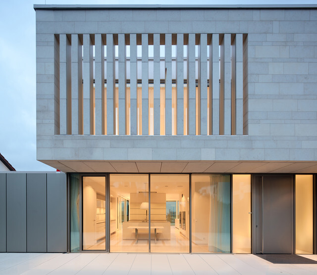 Modern house facade with glass fronts and wooden louver balcony; bright interior visible