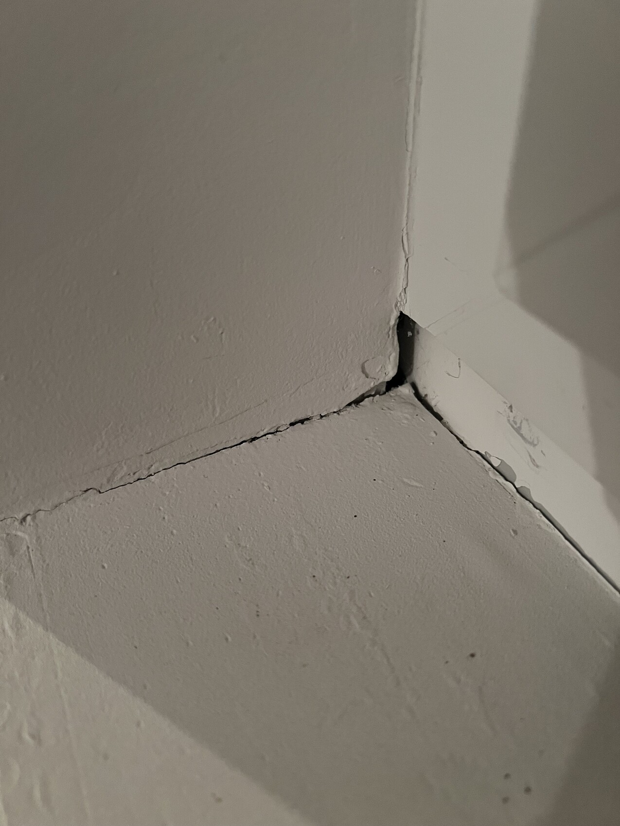 Close-up of a floor-to-wall corner with a crack in the joint and rough surface
