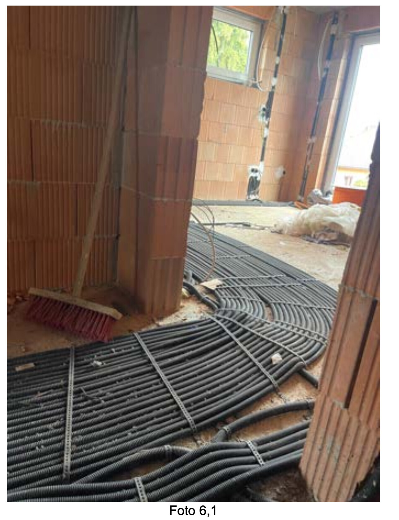 Interior construction site with red brick walls; cable bundles lying on the floor.