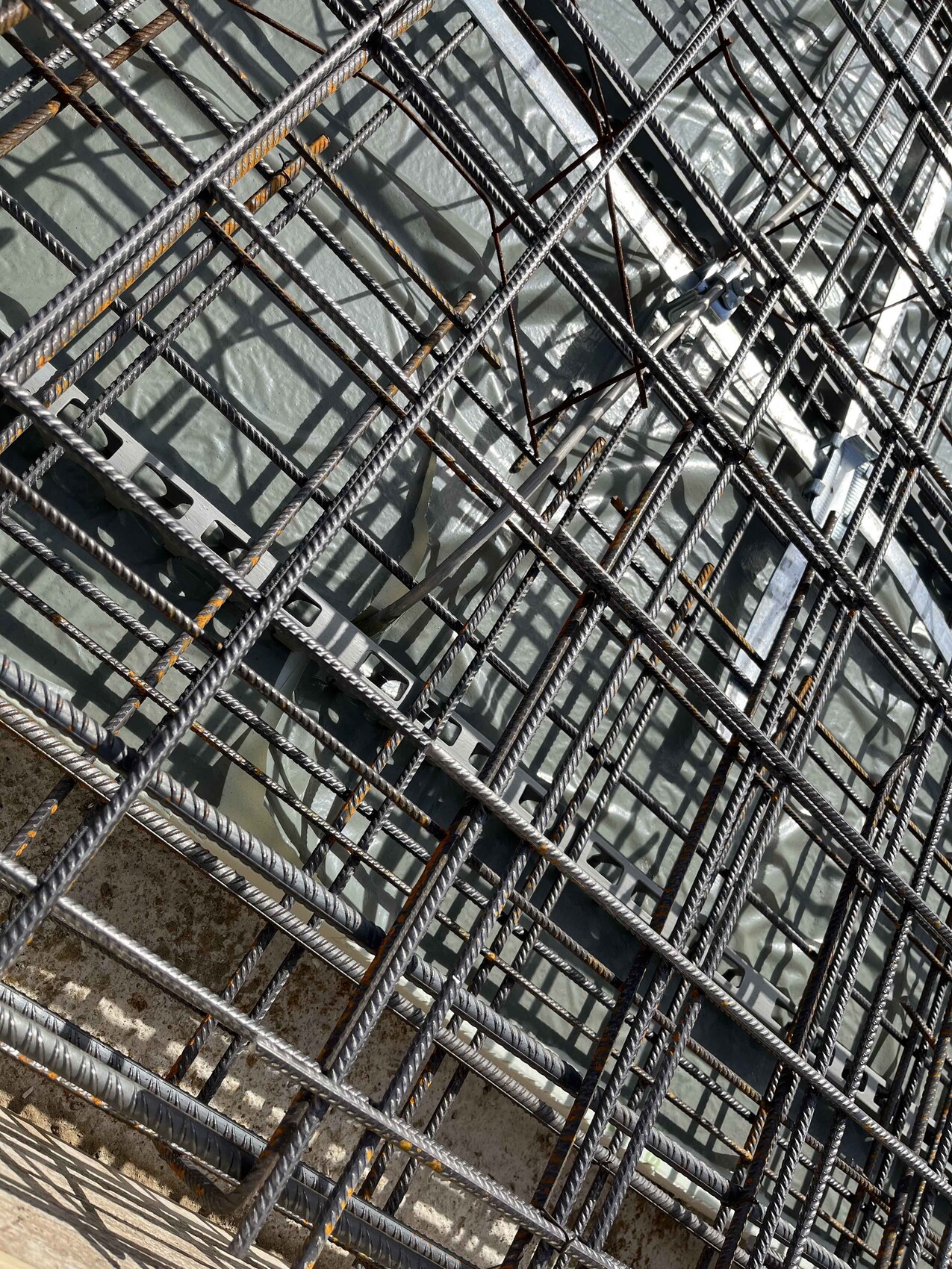 Steel reinforcement mesh made of many steel bars at a construction site with a concrete base