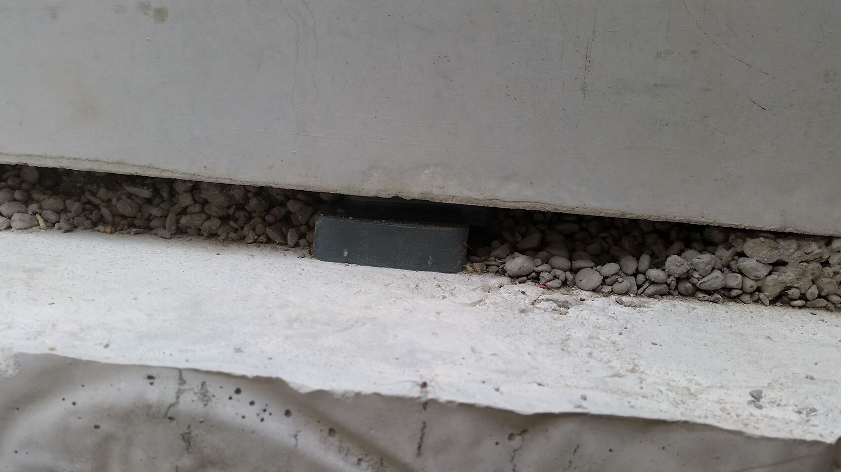 Concrete foundation slab with gravel base and a small black support